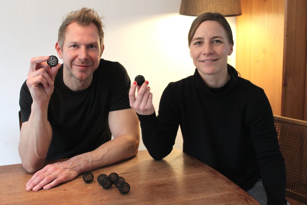 Susanne und Bernd Schmekel, die Erfinder der Sauberkugel, halten an einem Holztisch je eine Sauberkugel in die Kamera