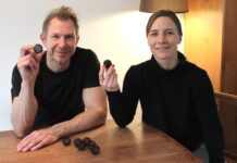 Susanne und Bernd Schmekel, die Erfinder der Sauberkugel, halten an einem Holztisch je eine Sauberkugel in die Kamera