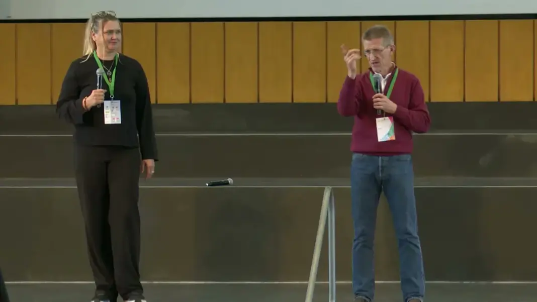Susi Erdmann und Horst Lutz stehen mit Mikrofonen auf der Bühne des Audimax
