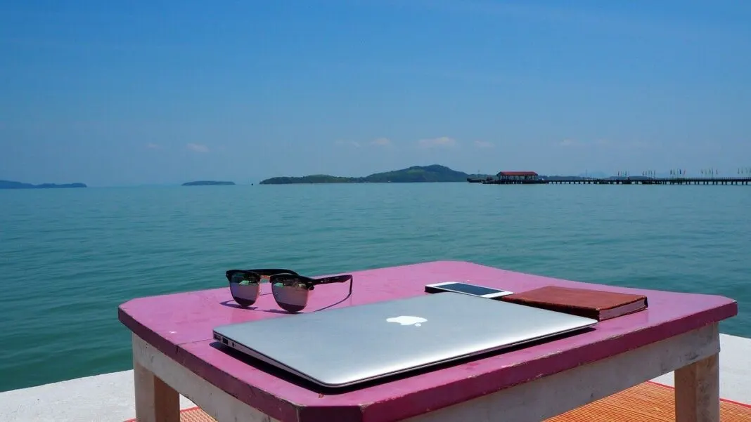 MacBook auf einer Ablage vor dem Meer als Symbol für freies Arbeiten von überall