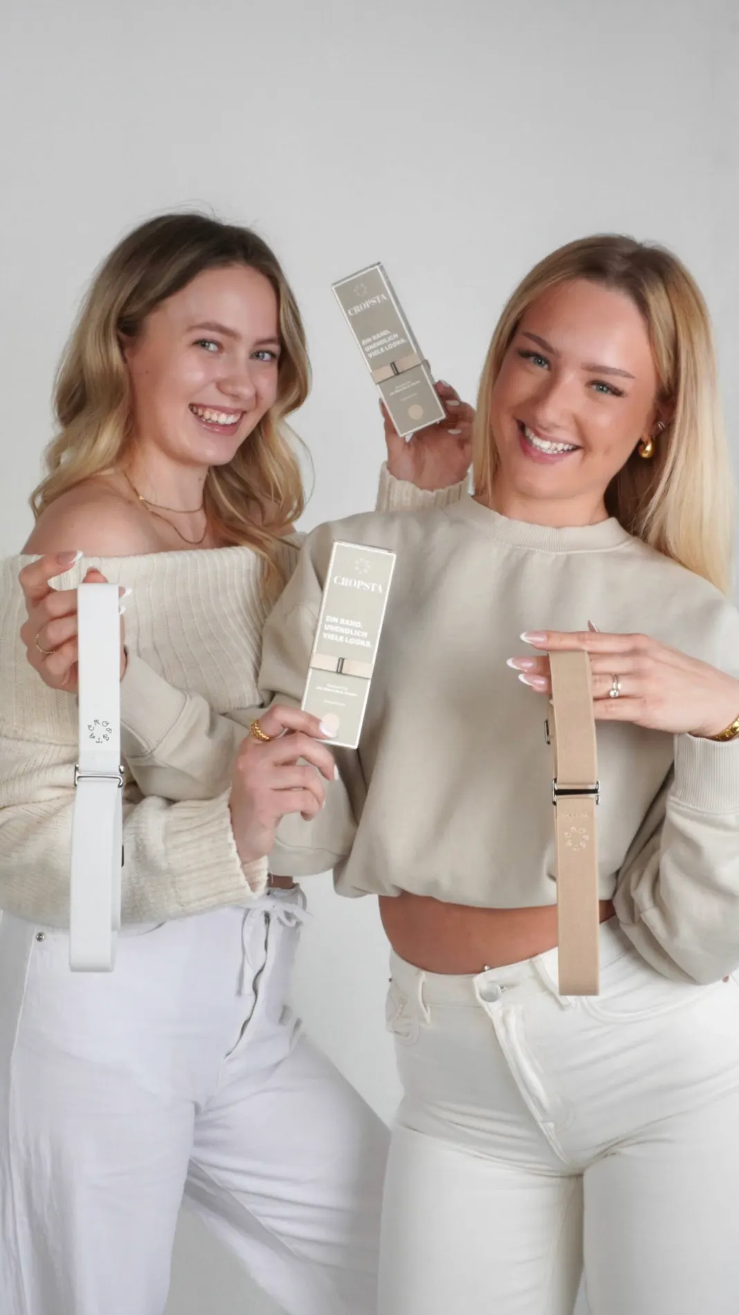 Zwei Frauen halten die elastischen Cropsta-Baender in Weiss und Beige sowie die Verkaufsverpackungen in die Kamera