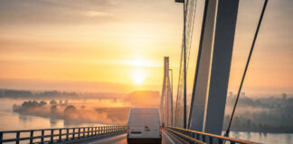 Lieferwagen fährt bei Sonnenaufgang über eine Rheinbrücke nach Frankreich