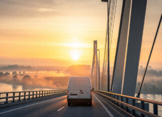 Lieferwagen fährt bei Sonnenaufgang über eine Rheinbrücke nach Frankreich