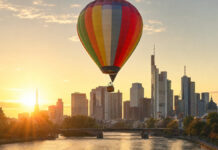 Heißluftballon steigt bei Sonnenaufgang vor der Frankfurter Skyline auf