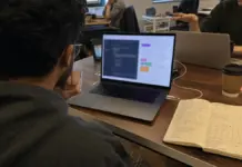Gründerin prüft einen App-Prototyp und Notizen zum Vibe-Coding-Toolvergleich.
