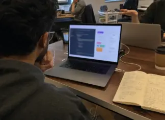 Gründerin prüft einen App-Prototyp und Notizen zum Vibe-Coding-Toolvergleich.