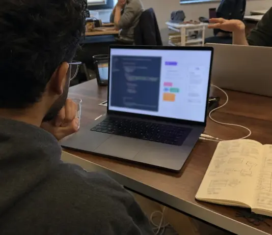 Gründerin prüft einen App-Prototyp und Notizen zum Vibe-Coding-Toolvergleich.
