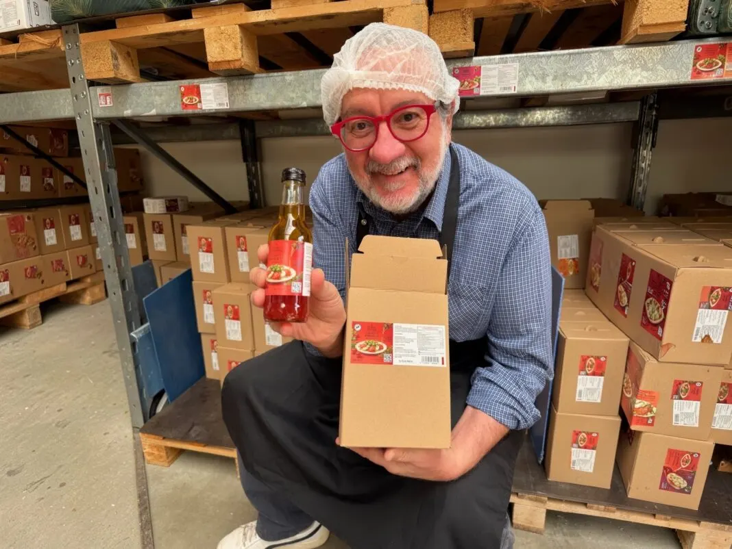 Mann mit Haarnetz hält im Lager eine Flasche Wunderdressing und einen Versandkarton